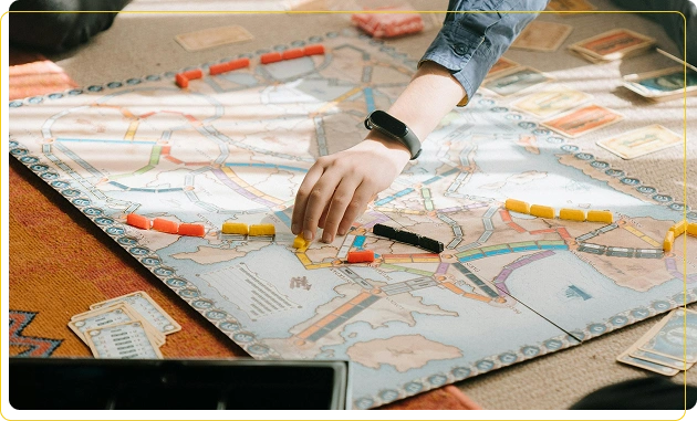 De jongen zet geconcentreerd een geel treintje op het bord van het bordspel.